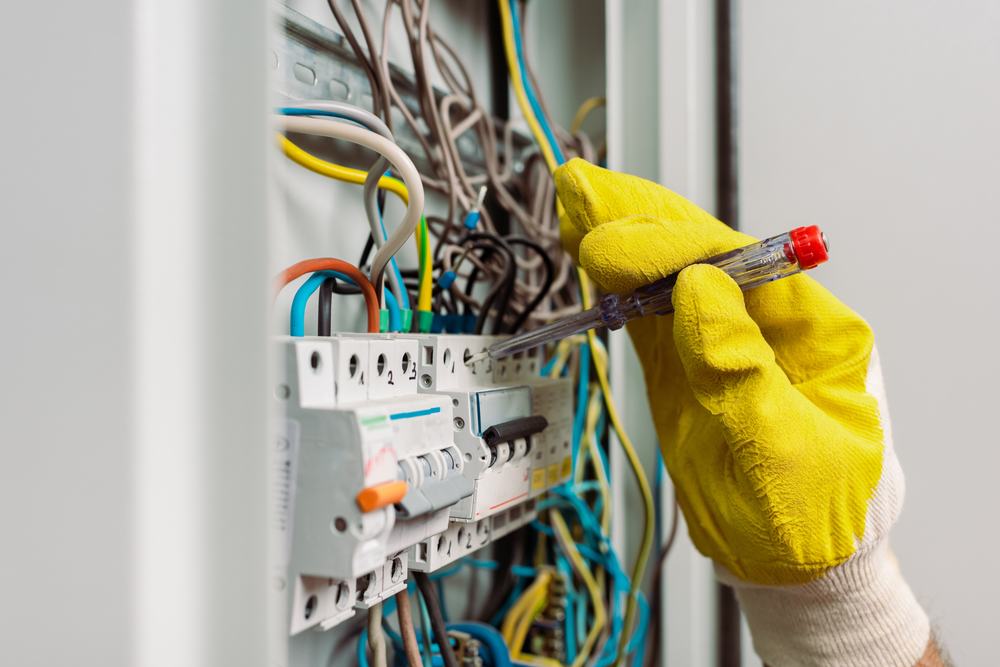 An electrician testing circuit breakers inside a residential distribution board.