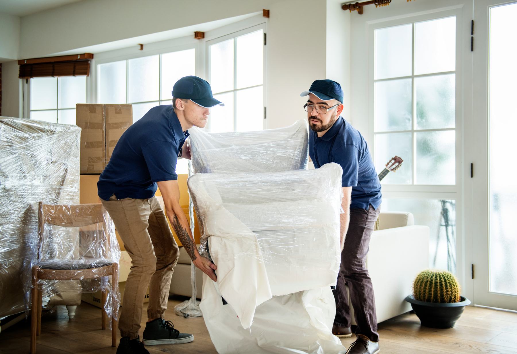 Two service professionals wrapping furniture inside a home