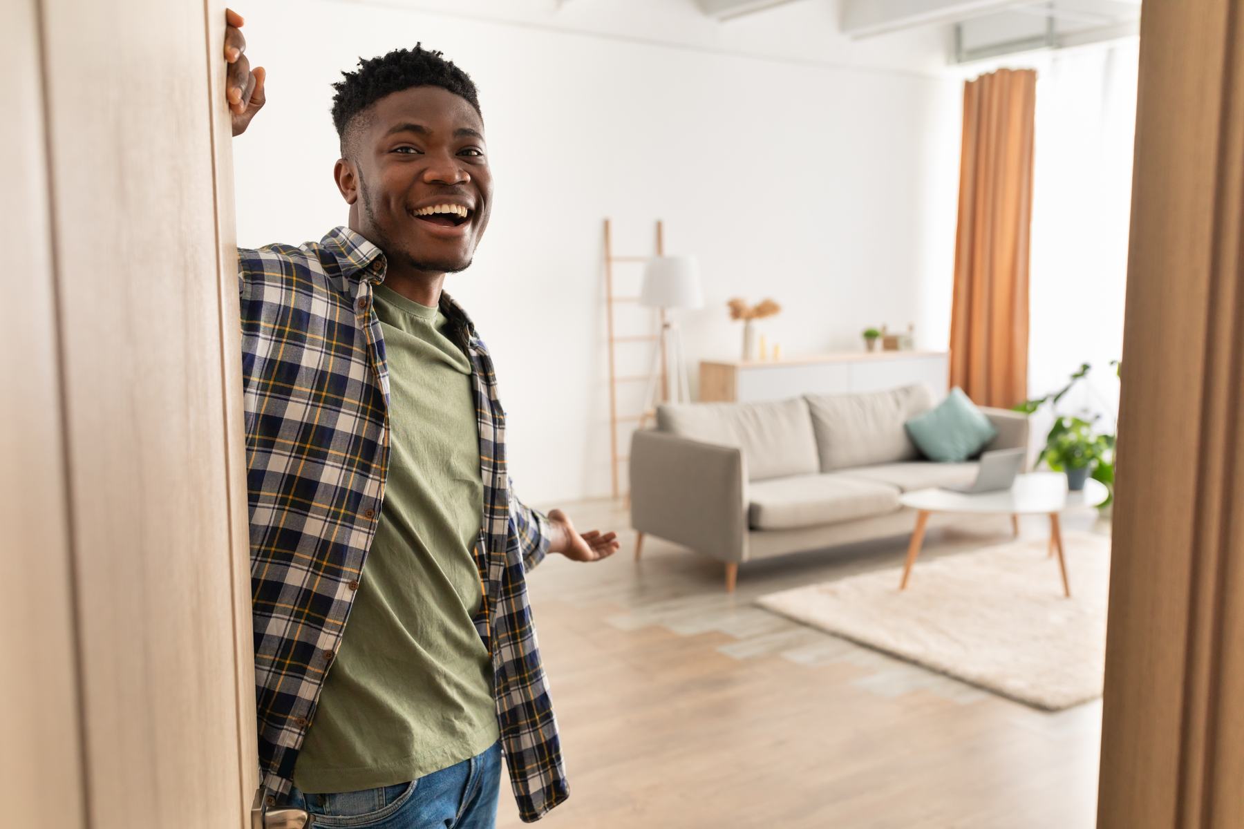 A smiling man opening the front door of his home